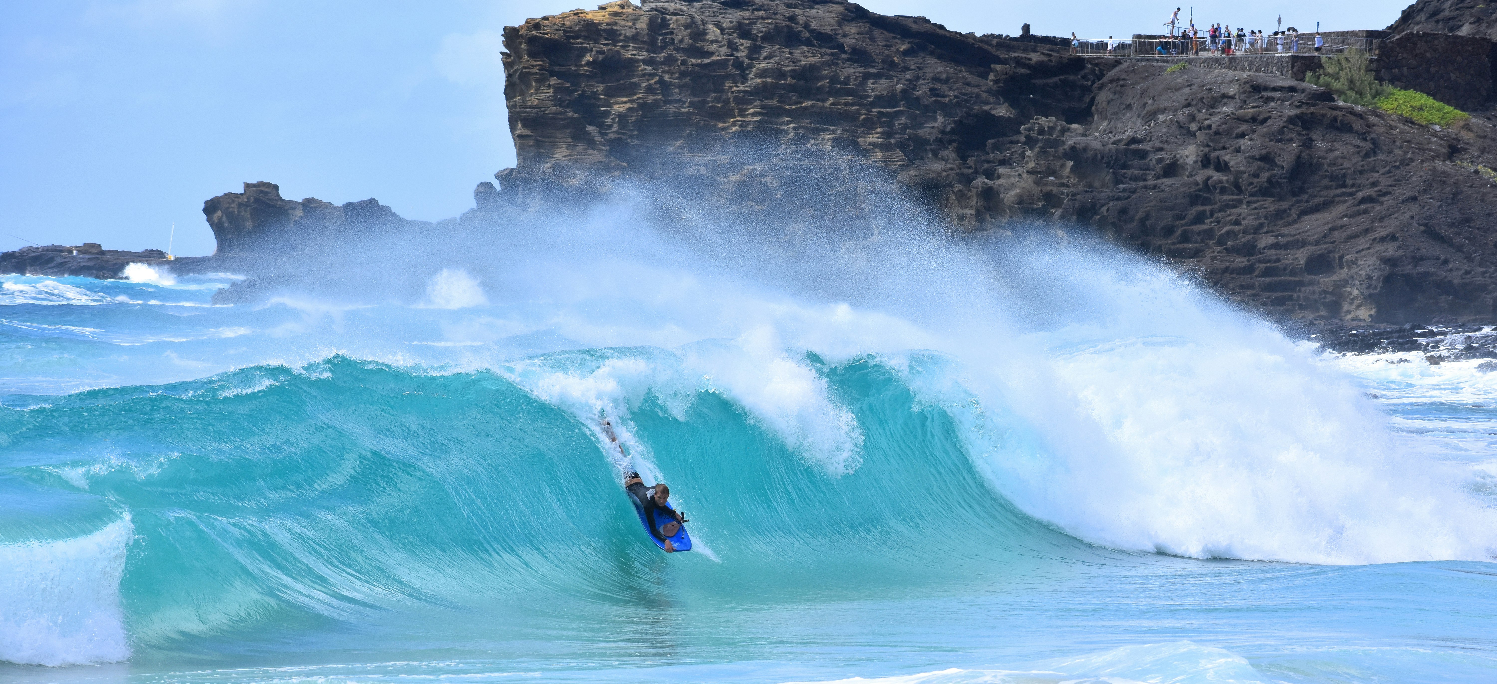 person riding on surfboard on body of water during daytime